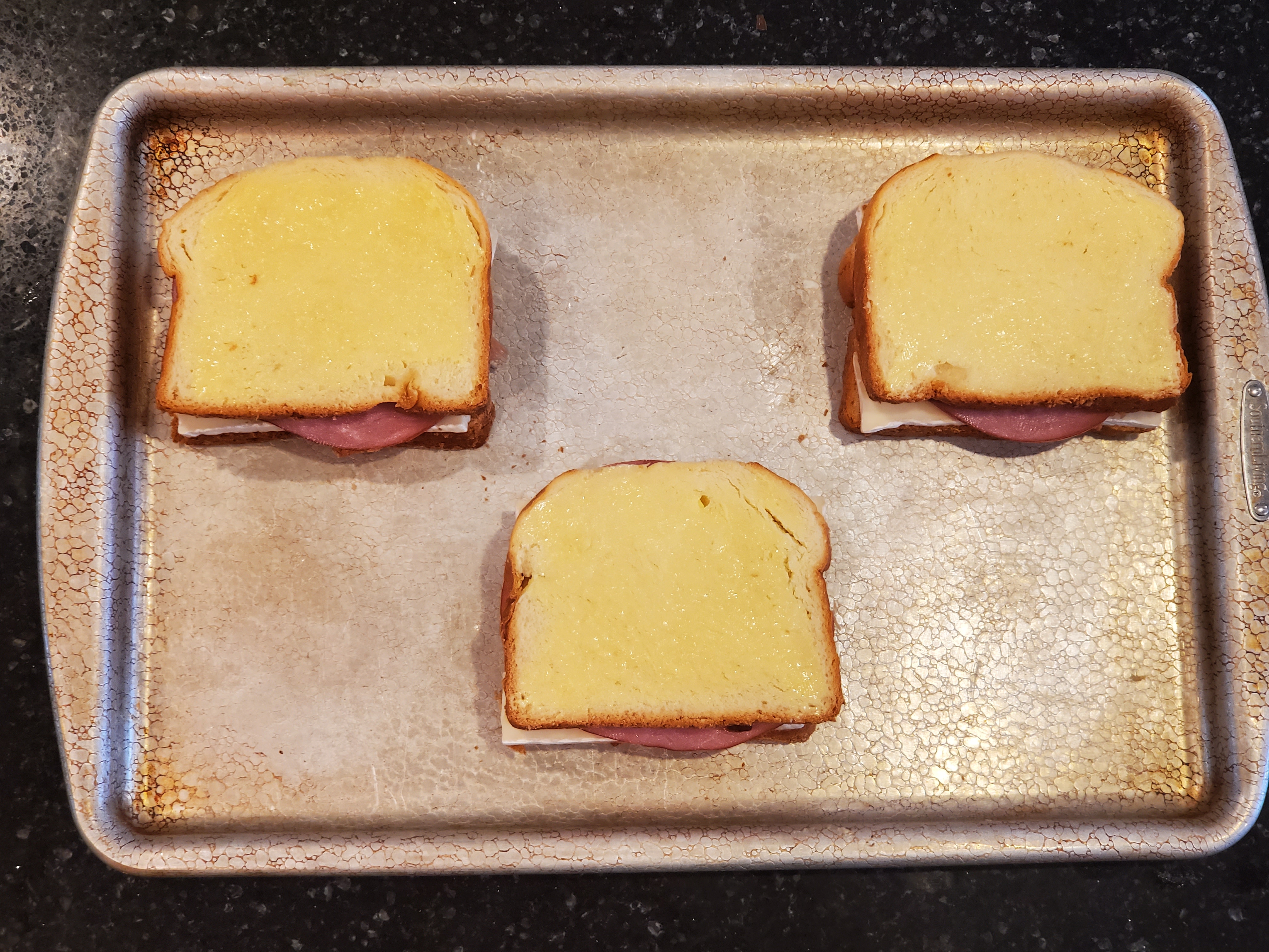 The three sandwiches are now assembled on top of the baking sheet, butter side up, ready to go in the oven.