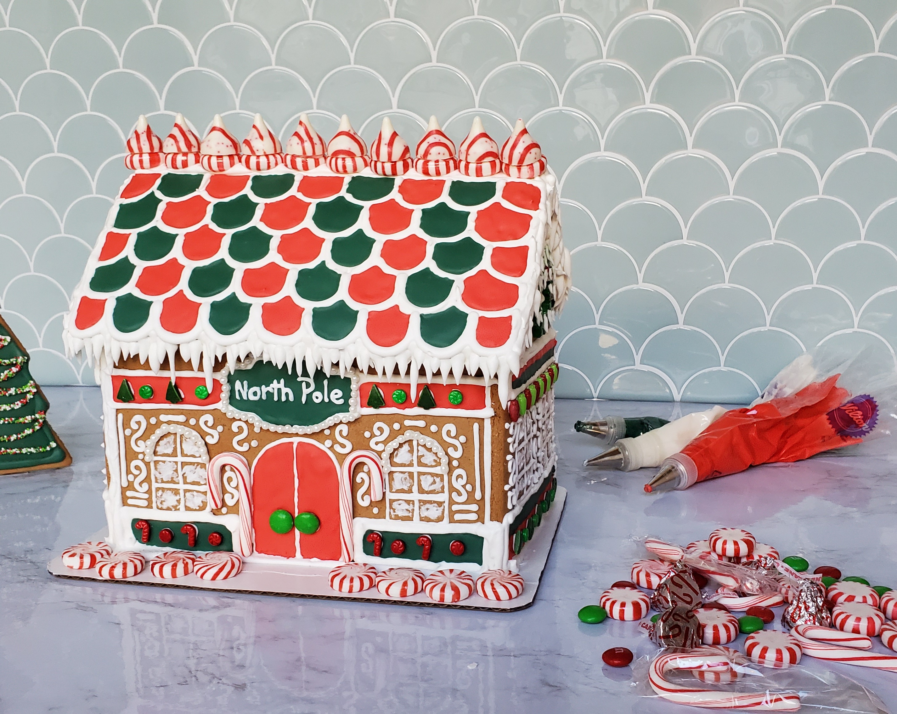 A gingerbread house surrounded by peppermints, candy canes, and royal icing.