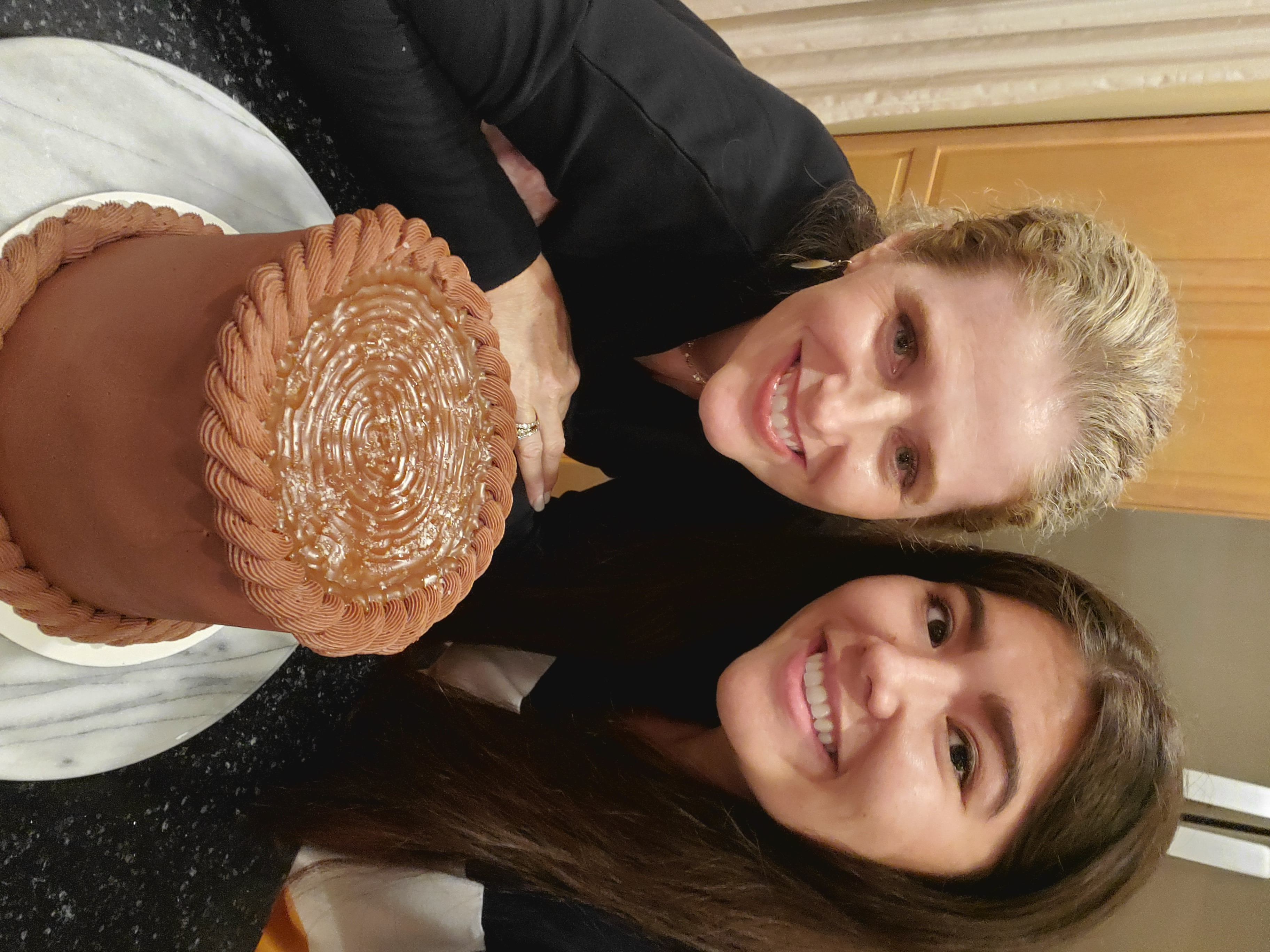 My mom and I smiling with her sea salt caramel chocolate buttercream layer cake that I made for her birthday.