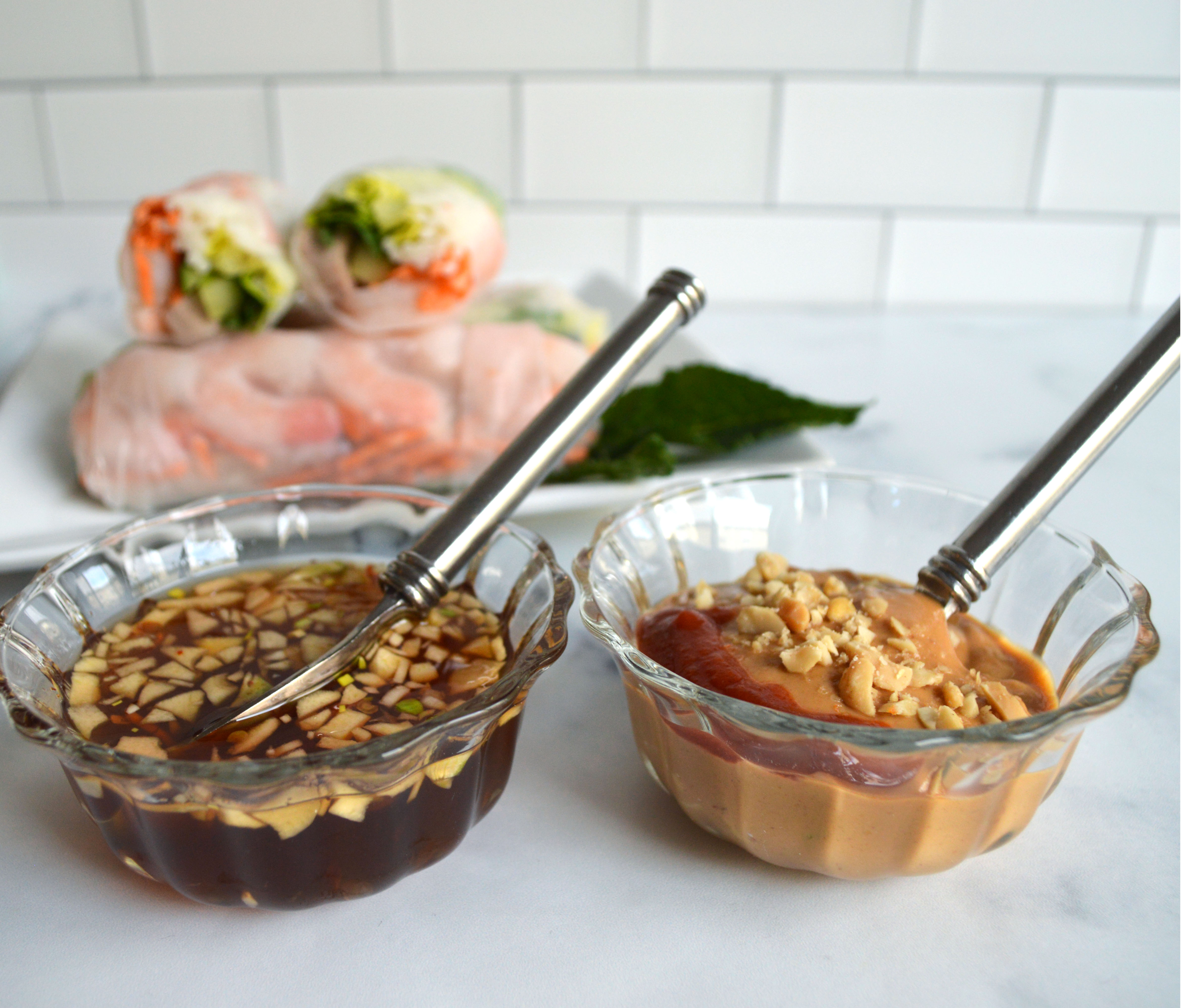 Nuoc Cham and peanut dipping sauce in the foreground and the Vietnamese spring rolls in the background.