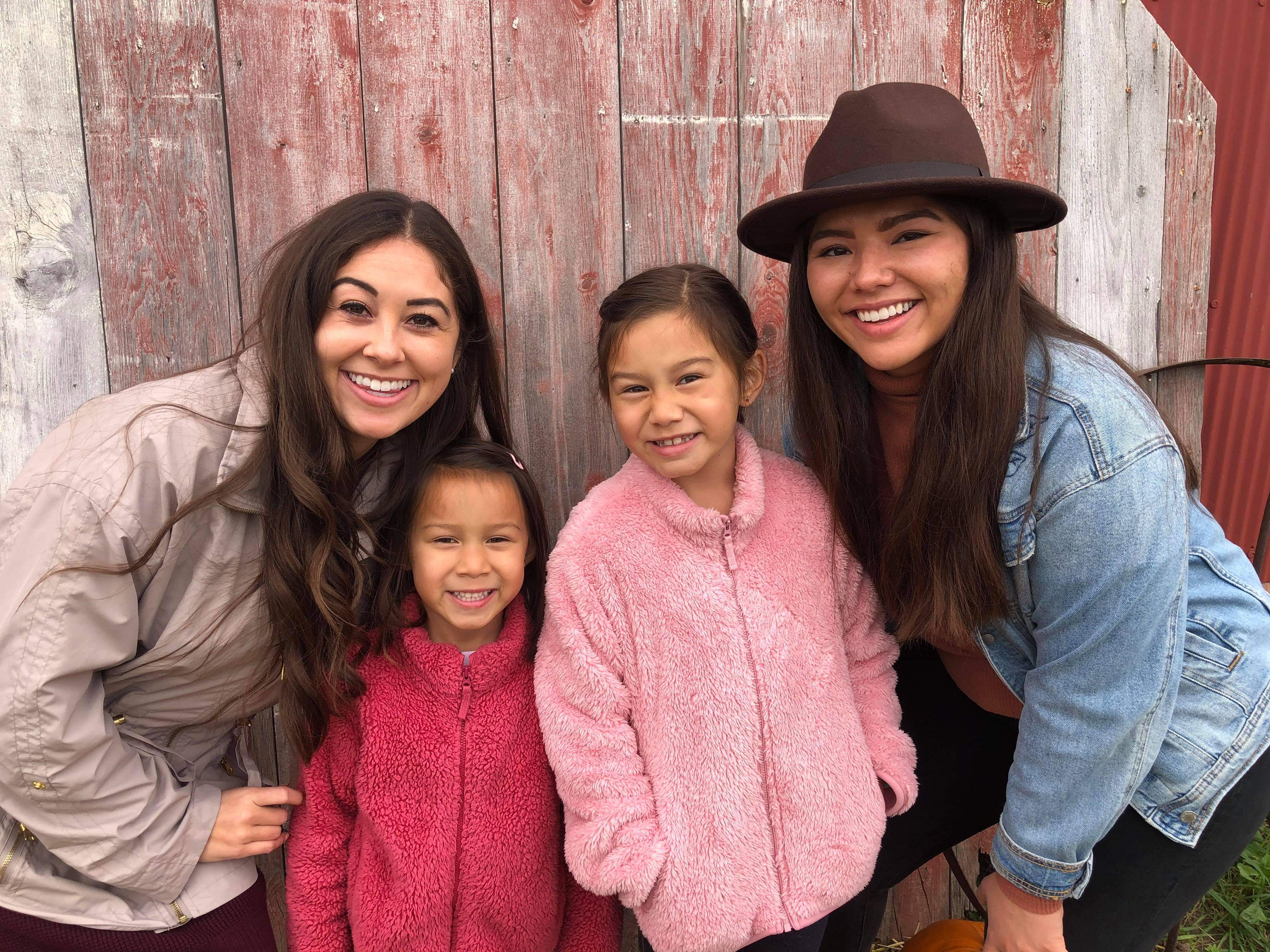 From left to right, Megan, Lana, Maya and I stand in front of a barn door smiling.