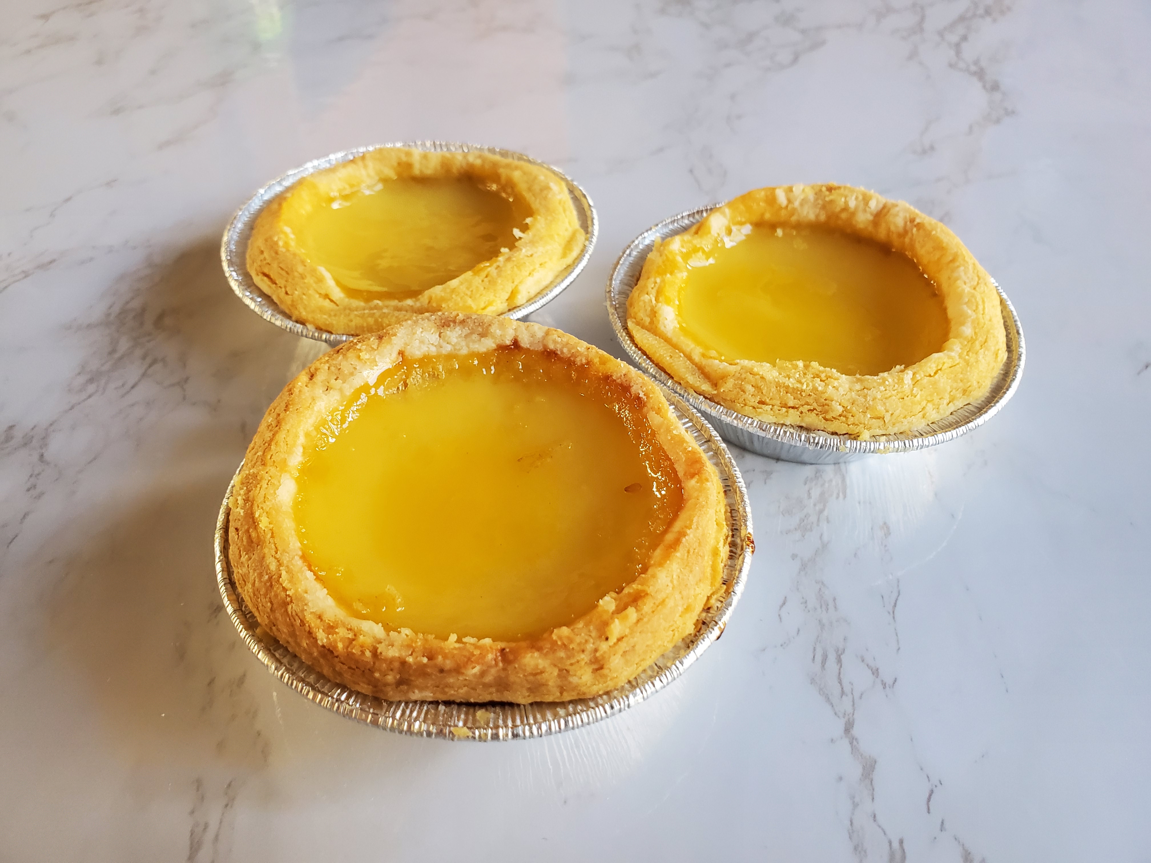 three chinese egg tarts on a marble coutertop