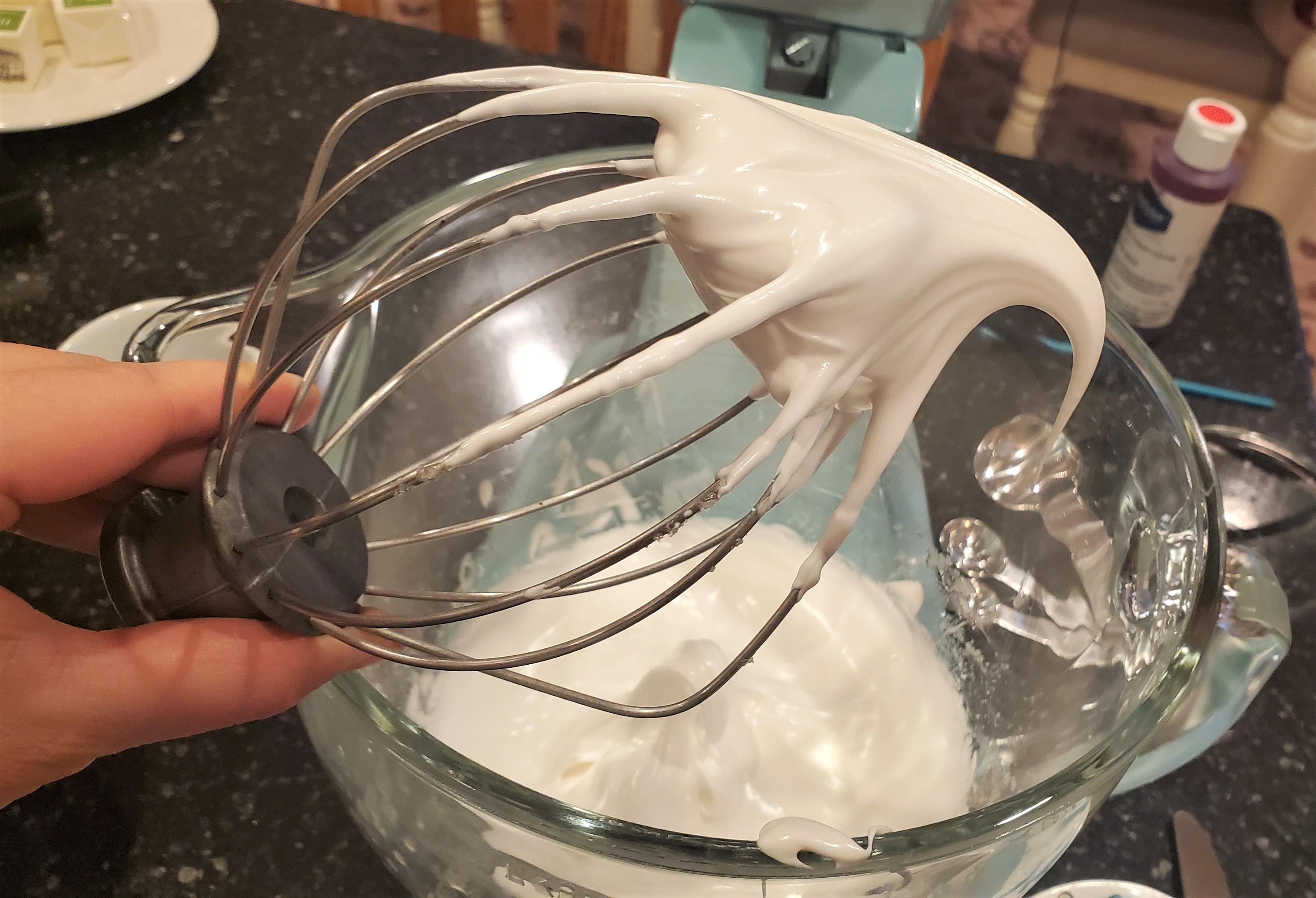 Stiff meringue for macarons on the whisk attachment of a kitchen aid mixer.